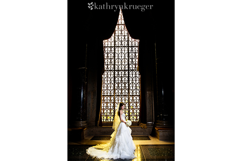 Full-length bridal portrait in front of intricate window.