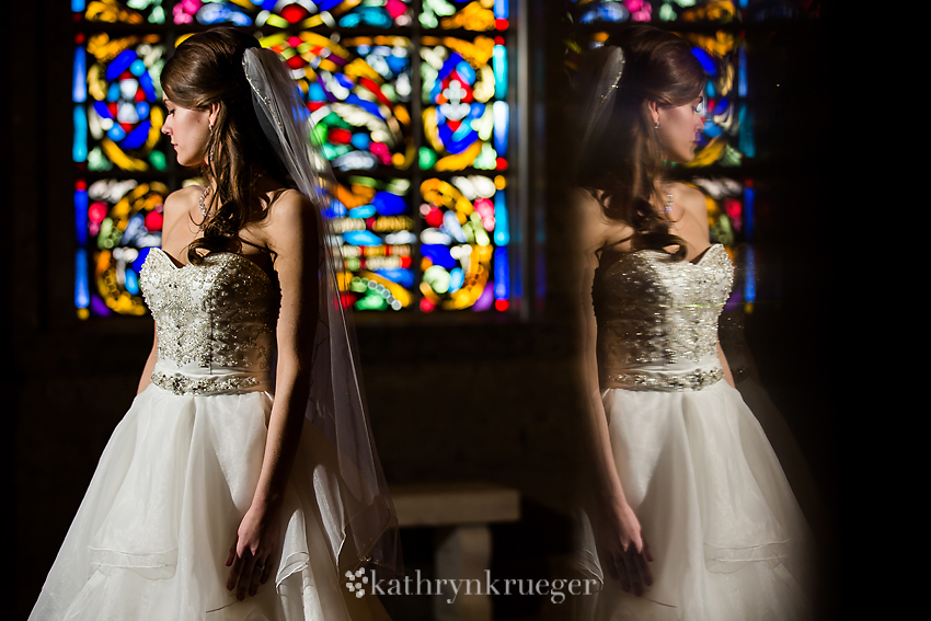 Bridal portrait in front of stained glass window with reflection. 