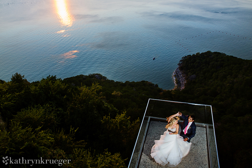 Groom spinning bride on ledge over Lake Travis in Austin, Texas.