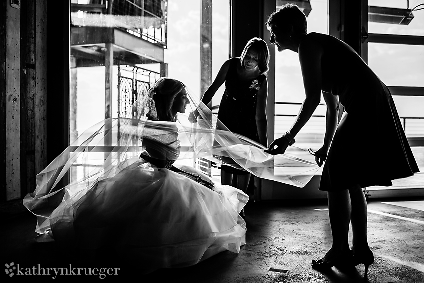 Black and white of bride getting veil on.