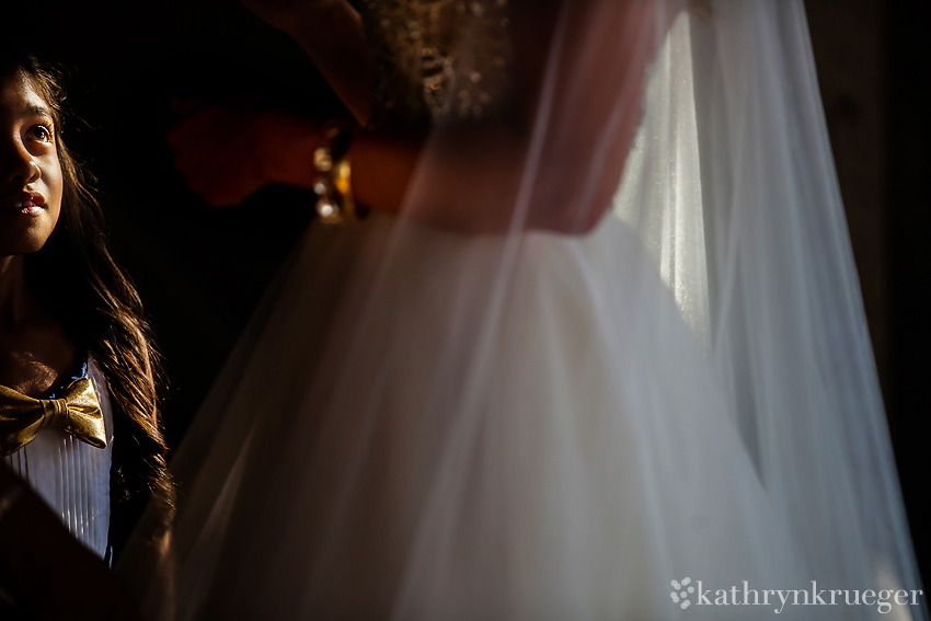 Flower girl watching bride getting dressed.