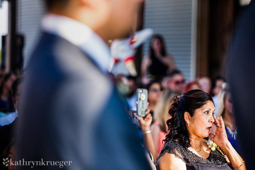 Mother of the groom wiping a tear during ceremony.