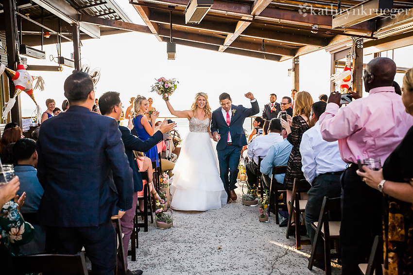 Bride and groom walking excitedly down the aisle after ceremony. 