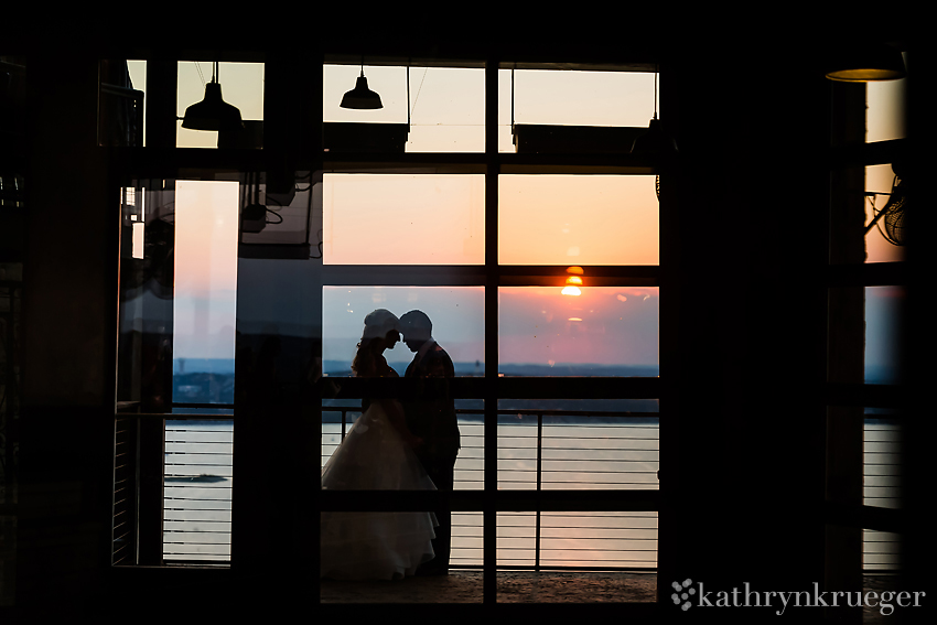 Silhouette of bride and groom in front of lake sunset. 