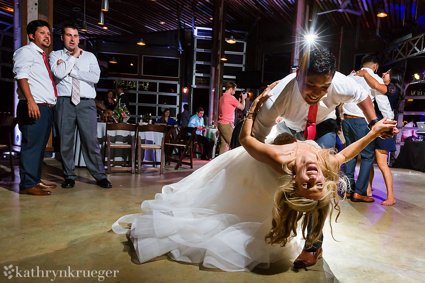 Groom dips bride while dancing.