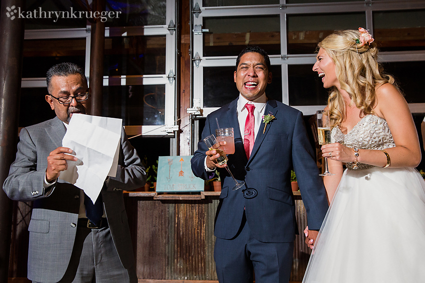 Bride and groom laugh during toasts.