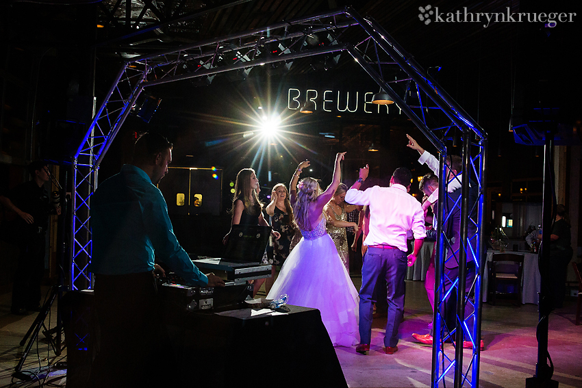 Wedding party dancing with DJ in the foreground.