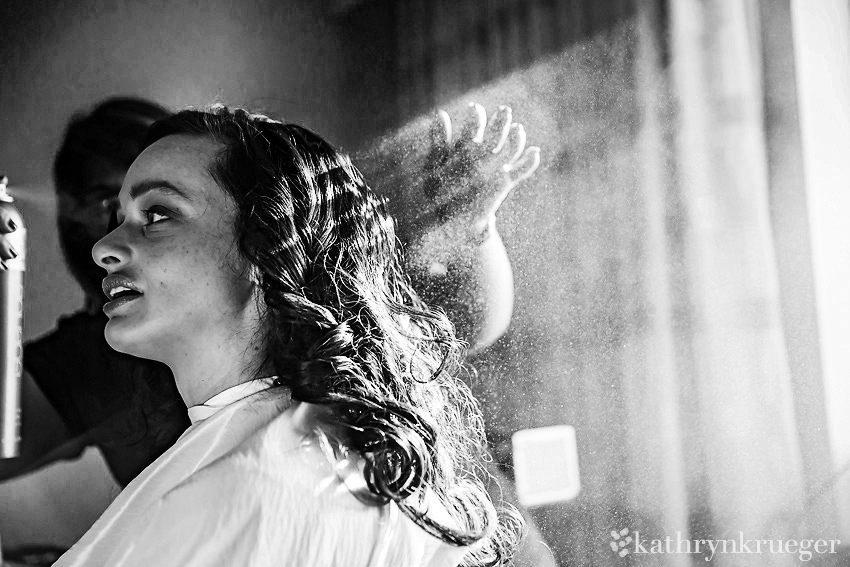 Black and white image of bride getting her hair sprayed.