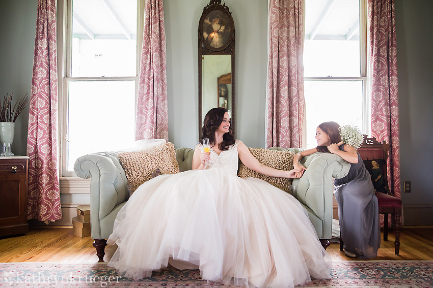 Bride and flower girl sitting and holding hands before wedding.