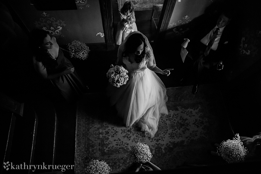 Black and white angle above the bride walking out of dressing room.