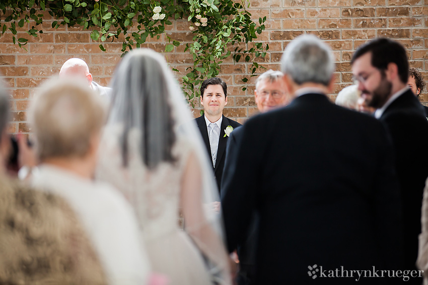 Groom watching bride walk down aisle.