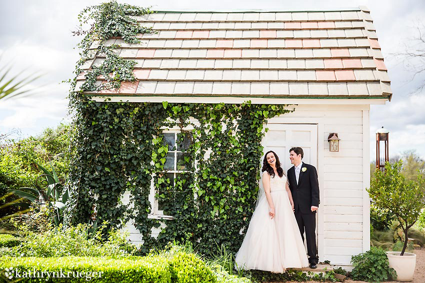 Bride and Groom laughing in front of white shed. 