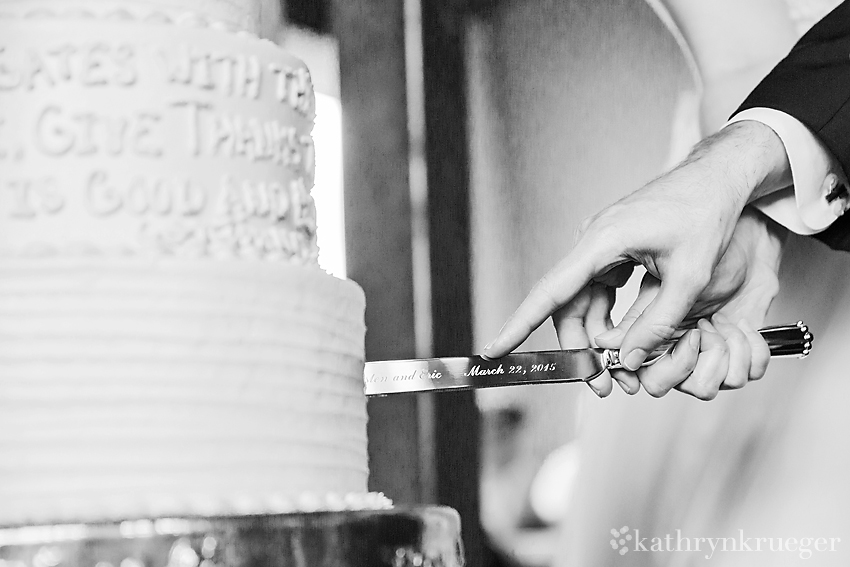 Black and white close up detail shot of bride and groom holding knife to cut cake.