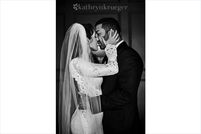 Black and white of bride and groom kissing passionately.