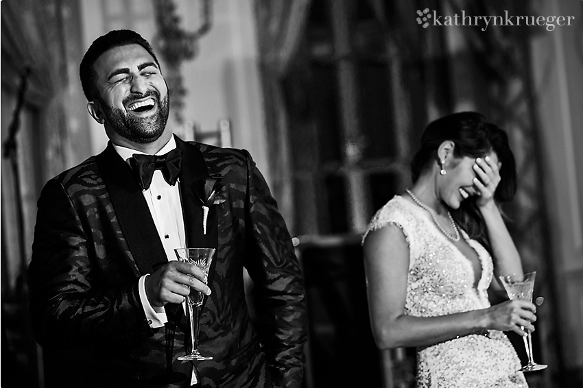 Black and white of bride and groom laughing during toasts.