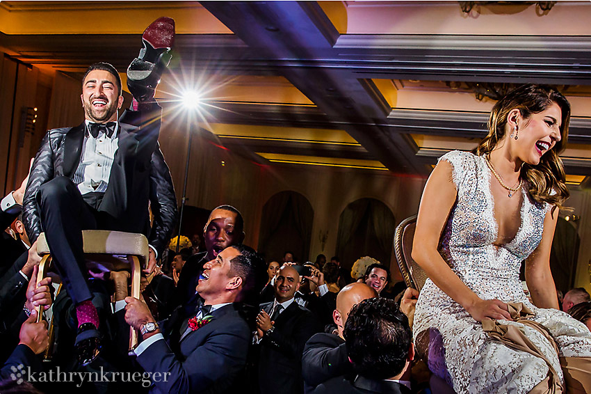 Groom and bride chair surfing through wedding crowd.