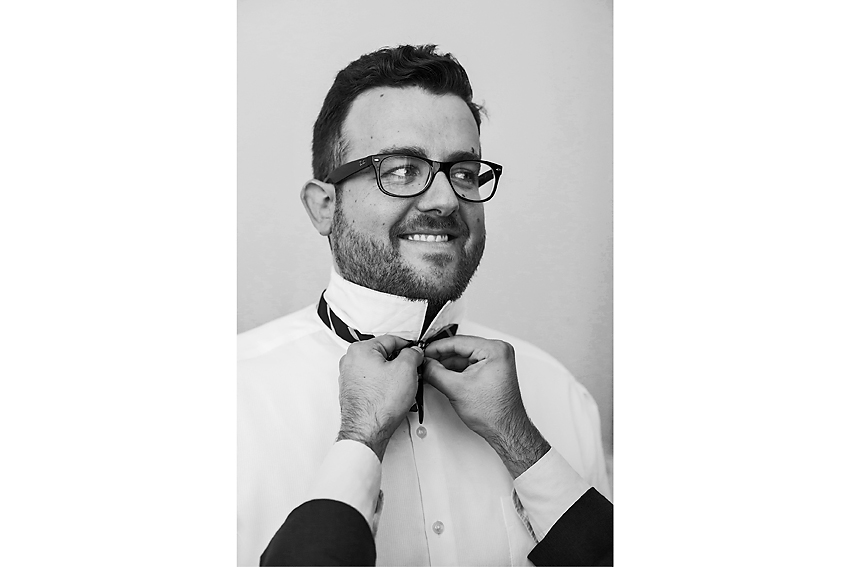 Black and white groom portrait getting help with bowtie.