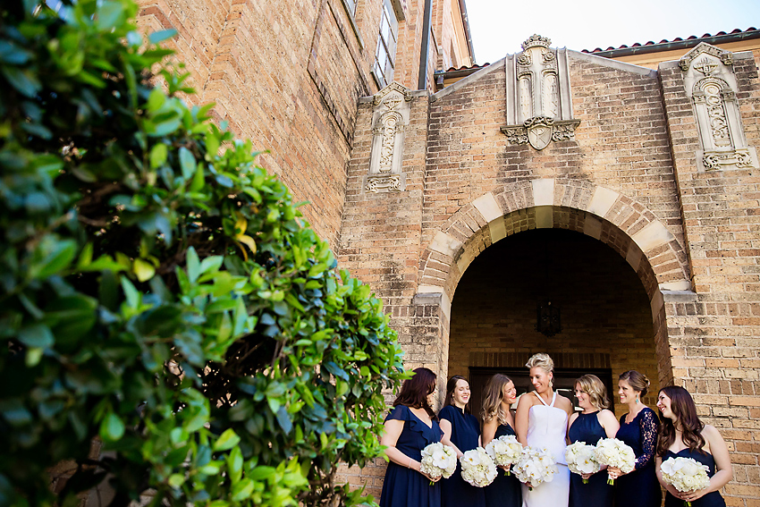 Bride and bridesmaids standing in front of archway. 