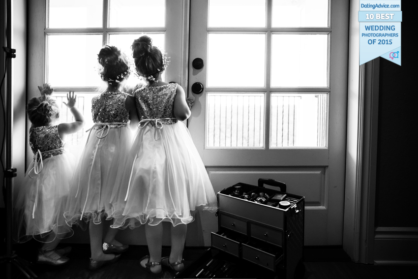 Black and white of three flower girls looking out glass doors.