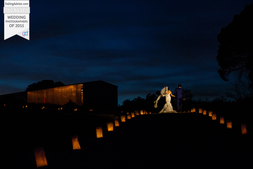 Bride and groom walking down a lantern pathway at dusk.