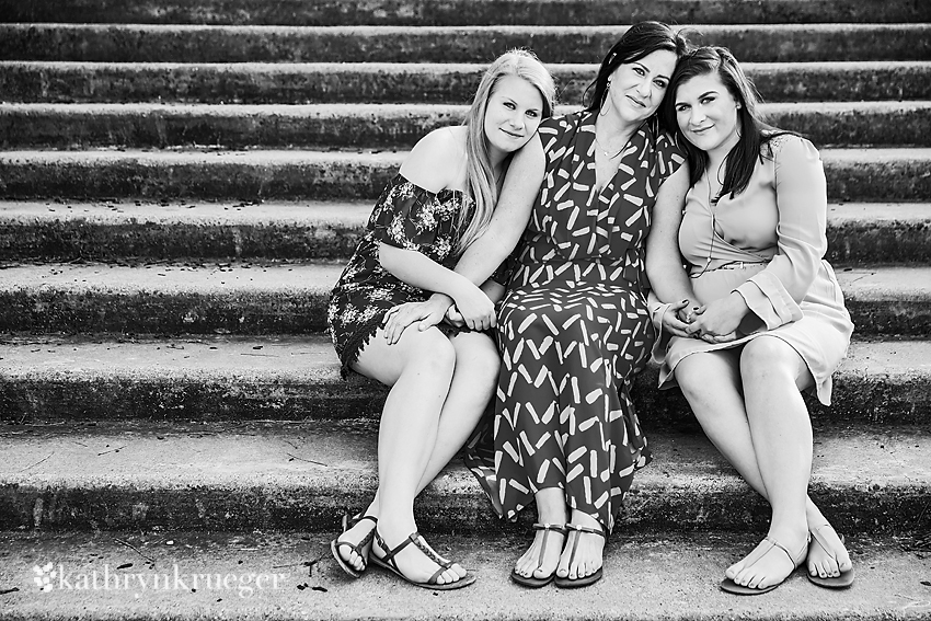 Black and white of mother and daughters sitting on steps.