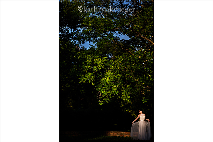 Bridal portrait standing in front of tall tree, bride holding skirt.