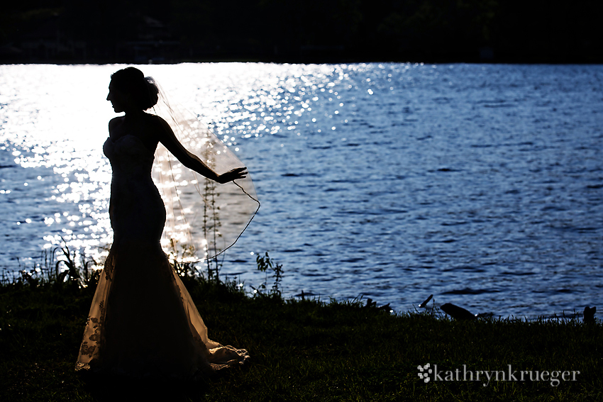 Bridal portrait silhouette in front of water.