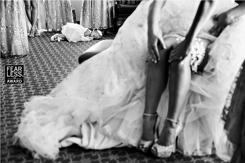 Flower girl asleep in the background of bride getting ready.