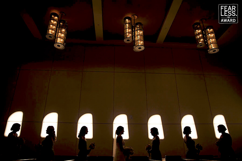 Bride and bridesmaids silhouette in front of windows.